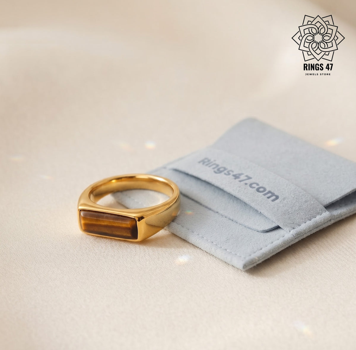 Bague homme œil de tigre plaqué or 18K posée près d'une pochette Rings47