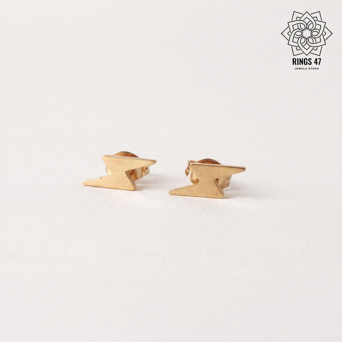 Boucle d'oreilles eclairs en acier inoxydable dorées sur fond blanc